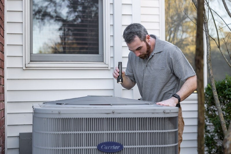 HVAC technician servicing a residential AC condenser unit