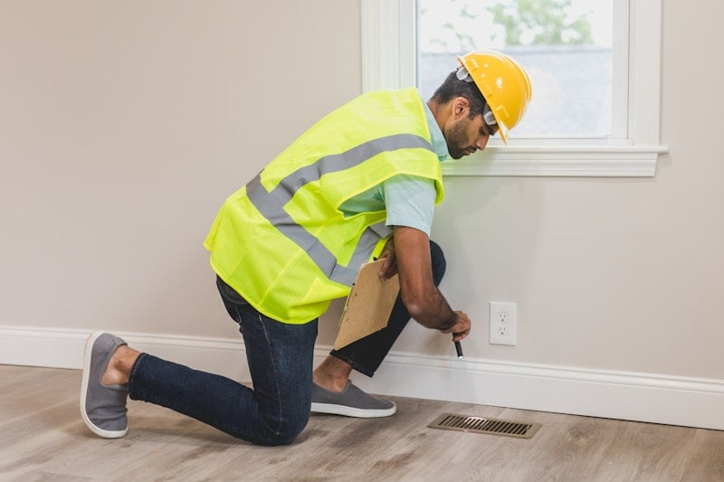 HVAC technician inspecting a floor heating vent